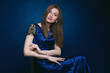 © Roman Kornev - a woman with long brown hair, in a blue dress, studio portrait on a blue background