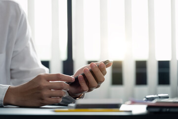 close up hand of businessman using mobile phone at office building, online business concept.