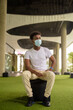 Full length shot of handsome black African man sitting wearing face mask while thinking