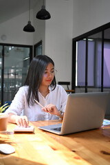 Wall Mural - Portrait of woman accountant in eyeglasses using calculator and working with laptop computer at office desk.