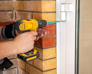 male hands of  construction worker tighten and fix  screws and self-tapping screw  with  electric cordless screwdriver for home improvement and building interior decoration.