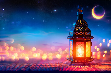 Wall Mural - muslim holy month ramadan kareem - arabic lantern with burning candle and bokeh glowing at evening -