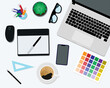 Graphic designer table from the top. On the table you can see color palette, coffee cup, graphic tablet, glasses, laptop and smartphone. freelancer messy working space.