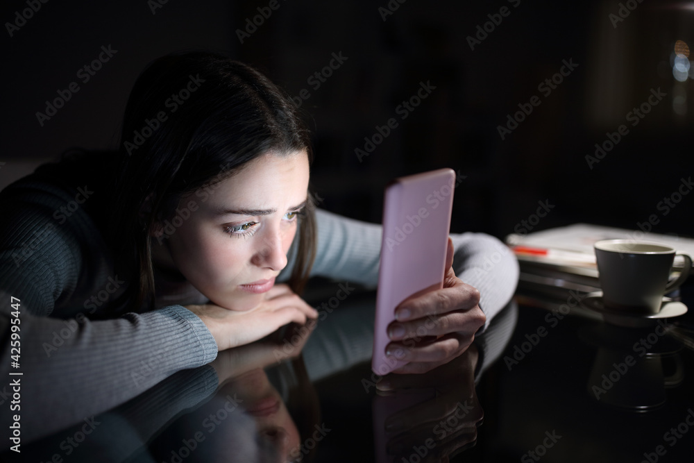 Sad female checking phone content in the night at home - obrazy, fototapety, plakaty 