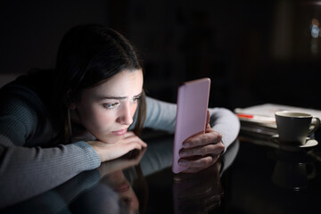 sad female checking phone content in the night at home