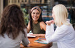 © liderina - Three students reading books in cafe and talking.