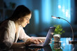 © PheelingsMedia - Happy woman writing on laptop keyboard in the night