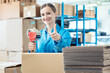 © Kzenon - Woman in factory warehouse packaging goods giving thumbs-up
