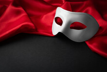 White Theatre Mask And Red Fabric On Black Background. Space For Text