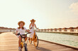 © JenkoAtaman - Carefree mother and daughter riding bicycles along wooden promenade