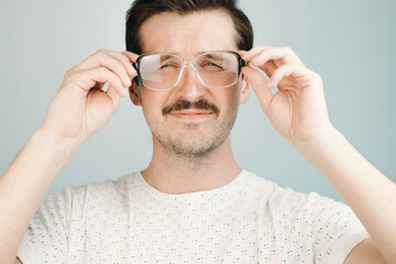 young man in big glasses squints at the camera, close-up. health problem concept, low vision, glasse