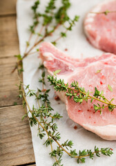 Wall Mural - Raw pork meat with thyme and spices on the rustic background. Selective focus. Shallow depth of field. 