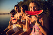 © Zoran Zeremski - Friends sitting on the edge of a pier enjoying on a summer day at the lake eating watermelon.