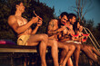 © Zoran Zeremski - Friends sitting on the edge of a pier enjoying on a summer day at the lake eating watermelon.