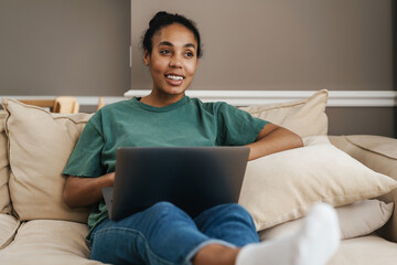 Smiling mid aged african woman sitting on couch