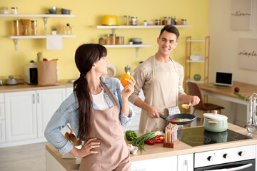 Wall Mural - Happy young couple cooking together in kitchen