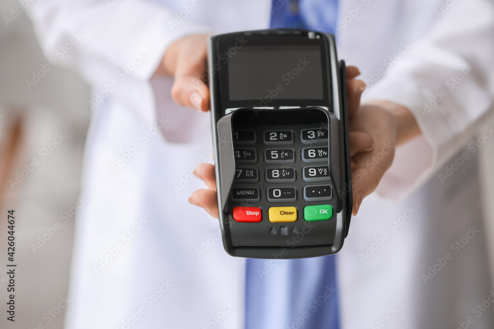Doctor with payment terminal in clinic, closeup