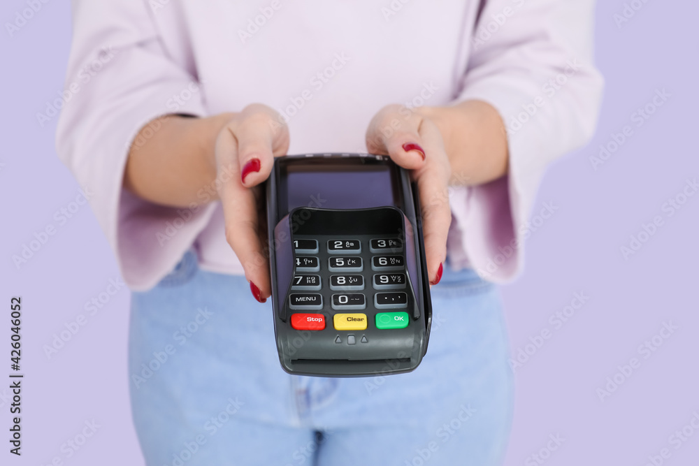 Young woman with payment terminal on color background, closeup