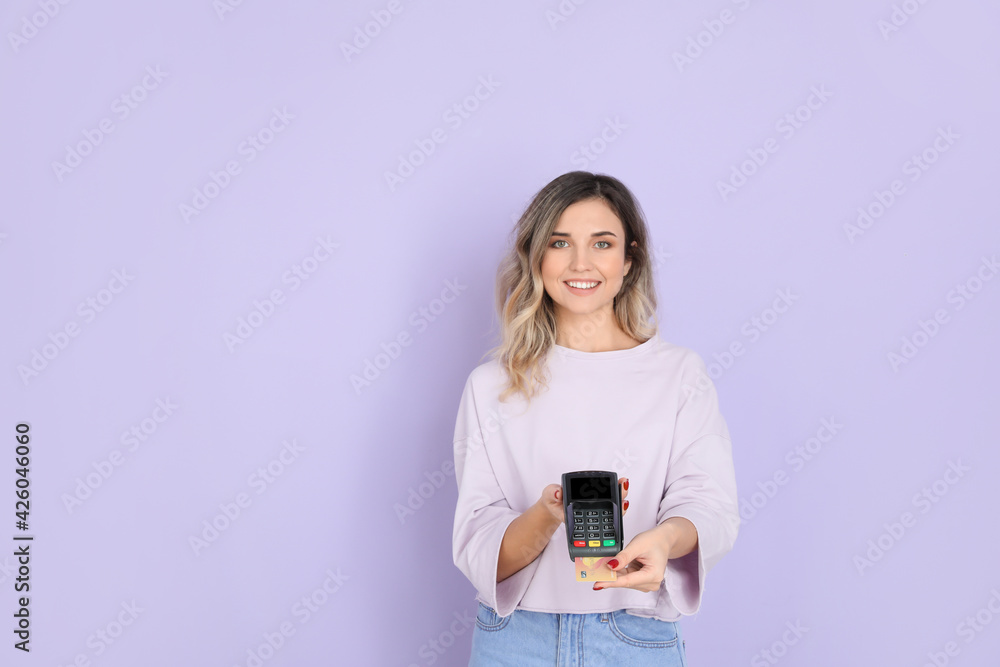 Young woman with payment terminal on color background