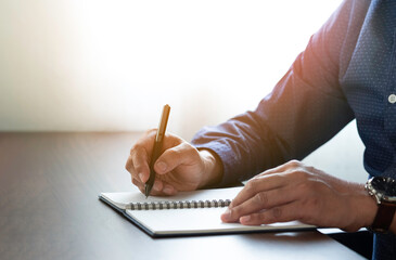 Wall Mural - Close-up of man hand using writing pen memo on notebook paper or letter, diary on table desk office. Workplace for student, writer with copy space. business working and learning education concept.