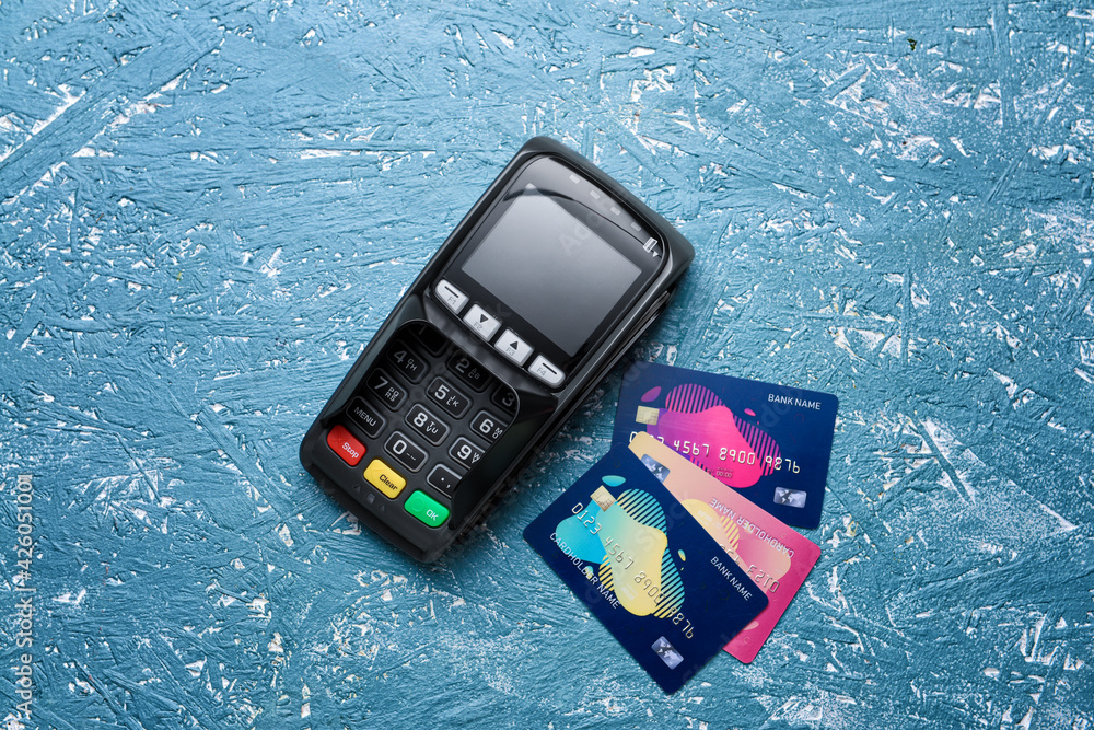 Payment terminal with credit cards on color background