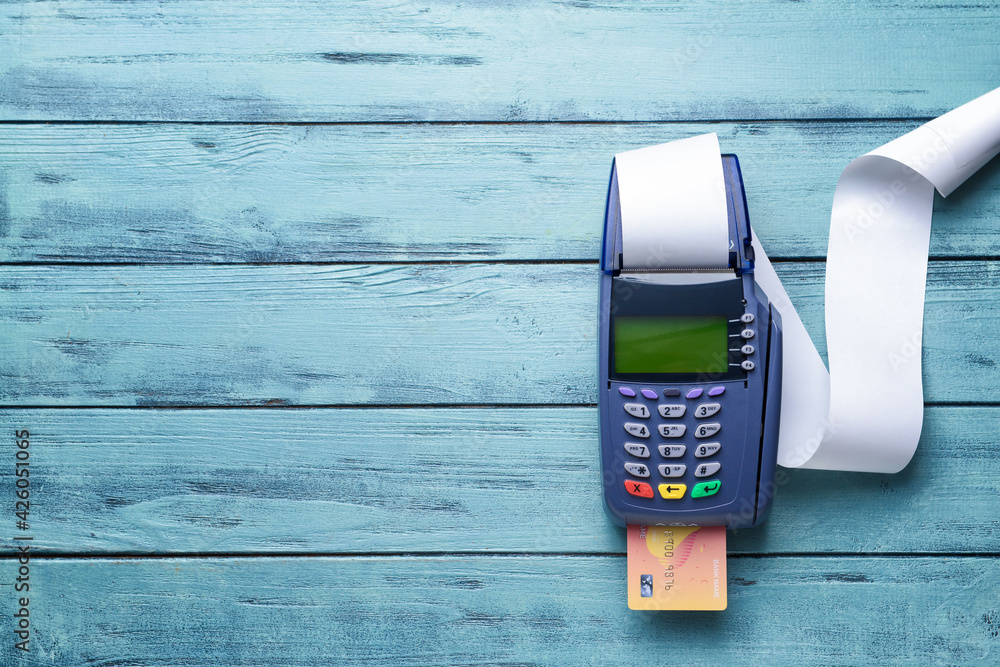 Payment terminal with credit card on color wooden background