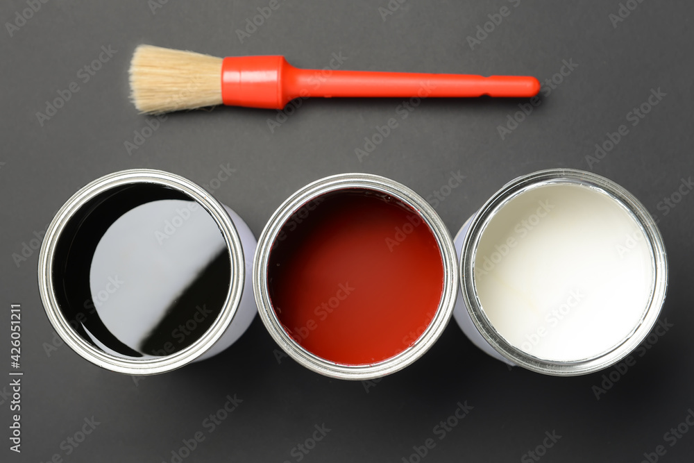 Cans of paints and brush on dark background, closeup