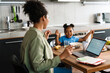 © Drobot Dean - Black woman working while having breakfast and playing with her daughter