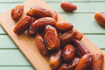 Board with sweet dried dates on color wooden background, closeup