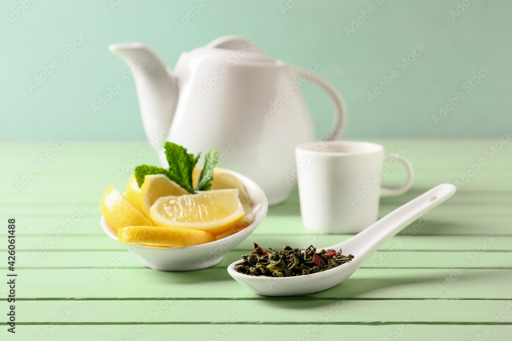 Composition with dry green tea and lemon on color wooden background
