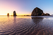 Haystack Rock And The Needles At Sunset, With Textured Sand In The Foreground, Cannon Beach, Clatsop County, Oregon, United States Of America