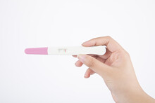 Isolated shot of a hand holding a negative pregnancy test kit on a white background