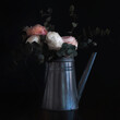 Flowers in a watering can, looking like an old still life painting, vintage and shabby mood
