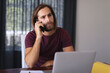 © wavebreak3 - Caucasian man sitting at table working from home and talking on smartphone