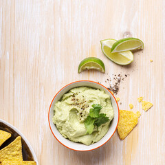 Canvas Print - Avocado hummus dip and corn chips on white wood table, top view