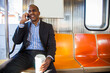 © Tetra Images - Black businessman talking on cell phone and riding commuter train