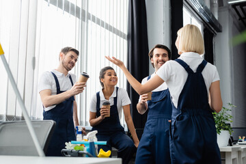 Wall Mural - Positive interracial colleagues of cleaning service talking during coffee break in office