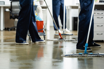 Cropped view of cleaners washing floor with mops in office