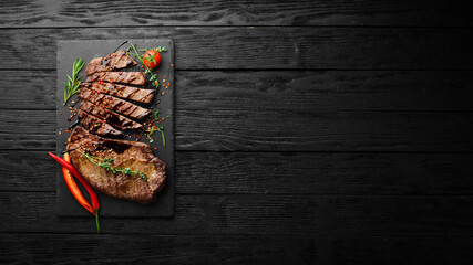 Wall Mural - Juicy veal steak with spices, thyme and rosemary. Top view. Flat lay top view on black stone cutting table.