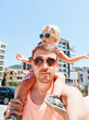 The daughter sits on dad's shoulders. Daddy carries a small child around his neck. Summer vacation concept near the sea. Portraits in sunglasses.