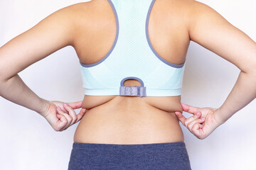 Wall Mural - behind back rear view photo of a young woman holding fat folds on her back. overweight. exercises fo