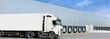 Loading docks of large warehouse with white truck under loading