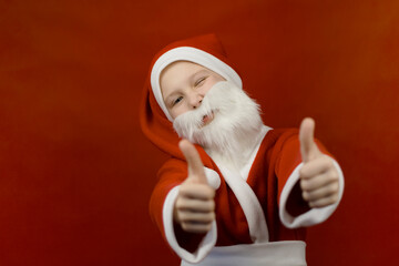 A boy in a Santa Claus costume holds his thumbs up.