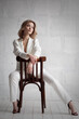 Beautiful sexy blonde in a white unbuttoned suit and underwear, posing sitting on a chair in the studio. Advertising, fashion, commercial, design.