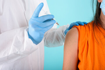 Doctor doctor injects vaccine with syringe against covid19 coronavirus. Cyan background