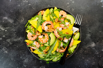 Shrimps, Mango and Avocado Salad with Walnut, Spinach and Arugula. Healthy Eating food concept Top view, gray background