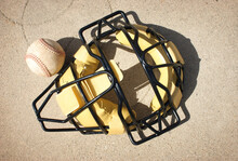 Baseball Catcher's Mask And Ball On Concrete