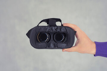 Man holds in his hands glasses for virtual reality and 360-degree video. VR helmet for the smartphone on a light background.