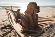 © Wavebreak Media - Happy african american woman lying in hammock on beach looking ahead