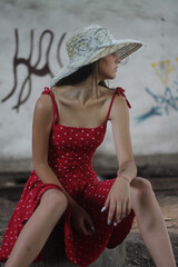 Canvas Print - Vertical shot of a young Caucasian lady wearing a red polka-dot dress with a summer hat